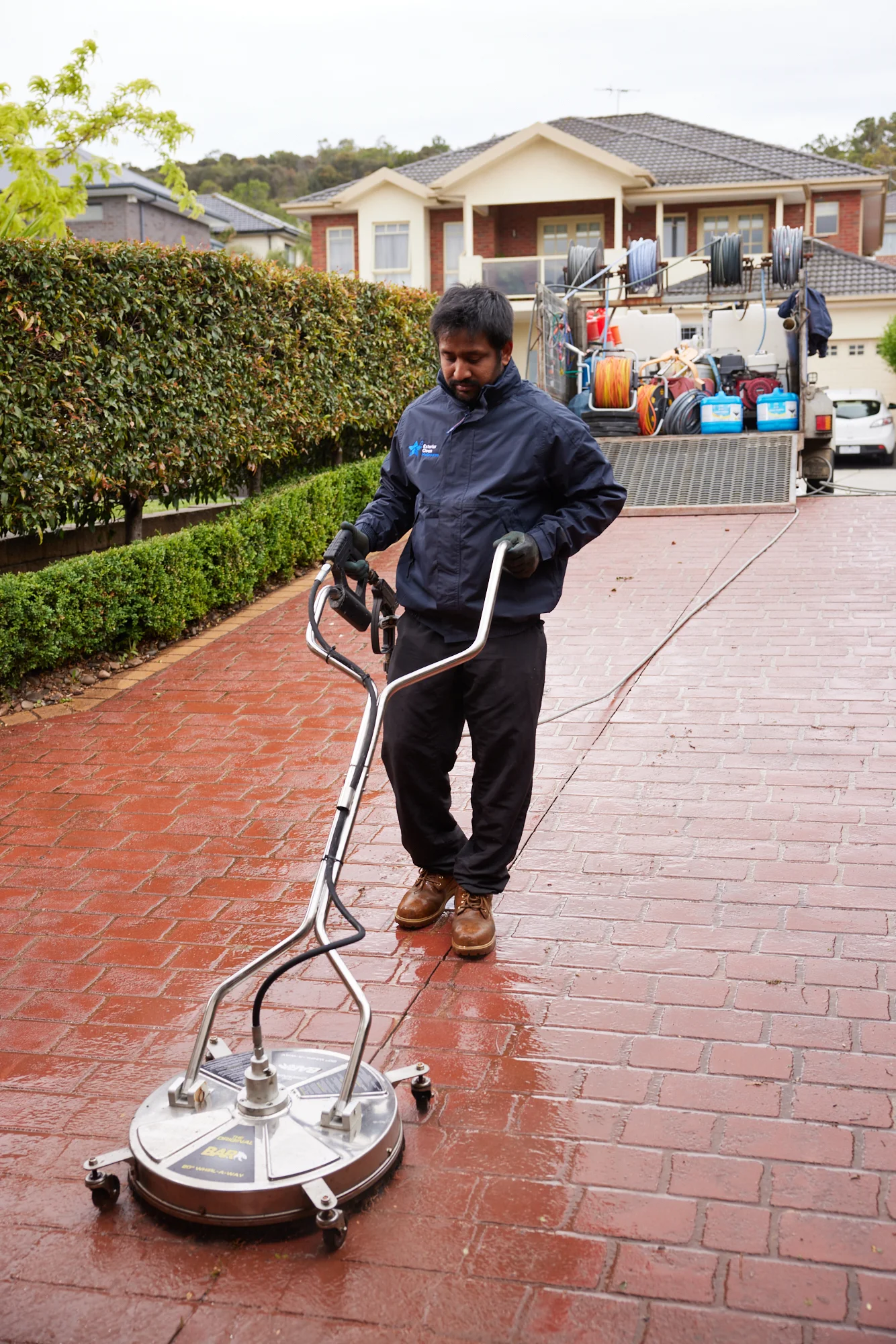 Technician using a surface cleaner on a paved driveway